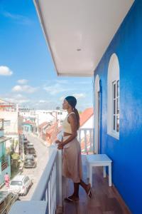 Eine Frau steht auf dem Balkon eines blauen Gebäudes. in der Unterkunft Hotel Casazul in Flores