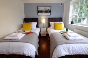a room with two beds with yellow and white pillows at Riverwalk Apartment One in Datchet