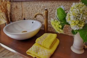 Un baño con encimera con fregadero y un jarrón con flores en Casa dos Amos en Costa da Morte. A Coruña, en Ponteceso