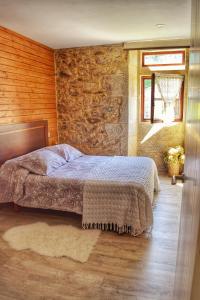 1 dormitorio con cama y pared de piedra en Casa dos Amos en Costa da Morte. A Coruña, en Ponteceso