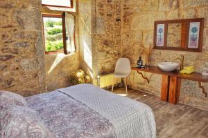 1 dormitorio con 1 cama y lavamanos en una pared de piedra en Casa dos Amos en Costa da Morte. A Coruña, en Ponteceso