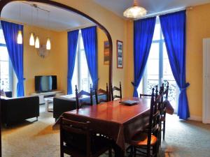 comedor con mesa y cortinas azules en Vaste appartement, lumineux, 8 couchages, en Eaux-Bonnes