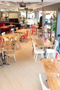 un restaurante vacío con mesas y sillas de madera en Ibis Saint Étienne - La Terrasse en Saint-Étienne