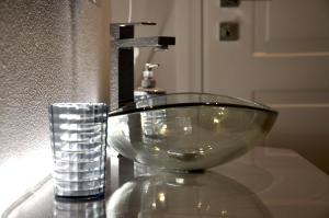 - un lavabo dans la salle de bains avec un bol en verre sur un comptoir dans l'établissement Luxury Apple Room Apartment Cagliari, à Cagliari