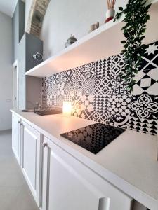 een keuken met een wit aanrecht met een muur met patronen bij Luxury Apple Room Apartment Cagliari in Cagliari