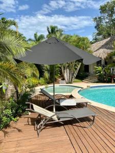 uma mesa e cadeiras com um guarda-sol ao lado de uma piscina em Villa tropical in private residence em Las Terrenas