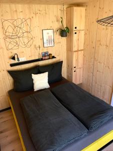 a bed in a room with a wooden wall at HJEM - Tiny Home in Bergatreute