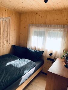 a bed in a wooden room with a window at HJEM - Tiny Home in Bergatreute