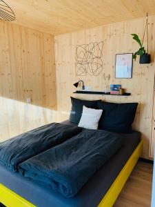 a bed in a room with a wooden wall at HJEM - Tiny Home in Bergatreute