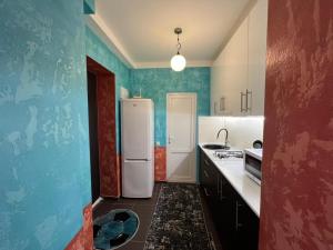 a kitchen with blue walls and a white refrigerator at Kavsadze street apartment in Tbilisi City