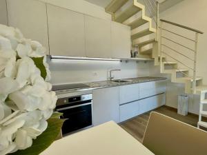 een keuken met witte kasten, een wastafel en een trap bij La Petite Maison in Colombaro