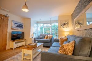 a living room with a blue couch and a tv at The Beach Escapes in Hythe