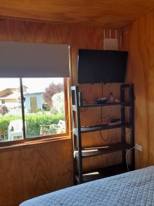 a room with a bed and a window and a television at LOS CLAVELES in Dichato