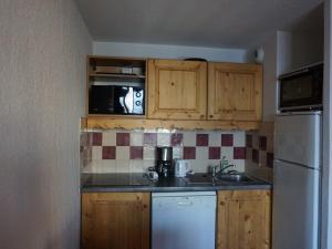 une cuisine avec des armoires en bois et un réfrigérateur blanc dans l'établissement Appartement de 2 Pièces avec Balcon et Parking à Proximité des Pistes à Orcières - FR-1-636-192, à Orcières