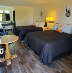 Habitación de hotel con 2 camas y mesa en Cactus Inn and Suites, en Mountain Grove
