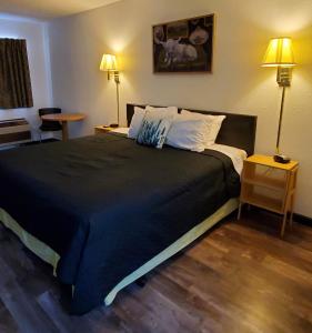 a bedroom with a large black bed with two lamps at Cactus Inn and Suites in Mountain Grove