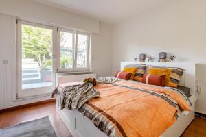 una camera da letto con un letto con un piumone arancione e una finestra di Luxe apt with parking & garden in wilrijk antwerp ad Anversa