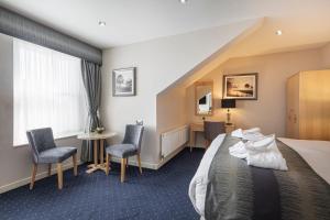 a hotel room with a bed and a desk and chairs at The Moorland Hotel, Haytor, Devon - The Coaching Inn Group in Haytor