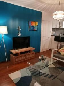 een woonkamer met een bank, een tafel en een tv bij Tropical Palms apartment Mauritius in Pointe aux Cannoniers