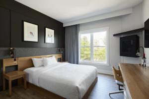 1 dormitorio con cama, escritorio y ventana en Espace 4 Saisons, en Magog-Orford