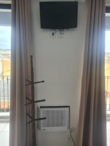 a flat screen tv on a wall next to a window at Hotel Mão de Fatima in Aparecida