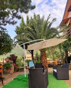 a patio with an umbrella and chairs on green grass at Affittacamere La Vigna in Serramezzana