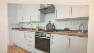 a kitchen with white cabinets and a black oven at Medway Chatham Waters in Gillingham