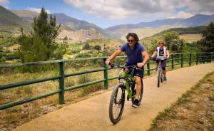 two people riding bikes on a path with mountains in the background at Civico 4 in Castrovillari