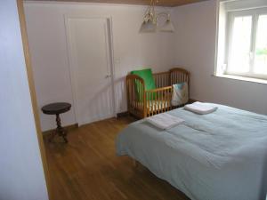 1 dormitorio con cama, cuna y ventana en Charmant gîte Haut-Marnais, en Montcharvot
