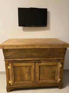a wooden table with a television on a wall at Gîte à la ferme chez Félix et Marie-Ca in Vallecalle