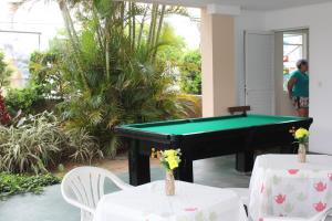 una mesa de billar en una habitación con 2 mesas y sillas en Floripa Hostel Barra da Lagoa, en Florianópolis
