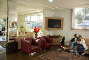 Hotel Dan Inn Express Foz do Iguaçu في فوز دو إيغواسو: رجل وامرأة يجلسون في غرفة المعيشة