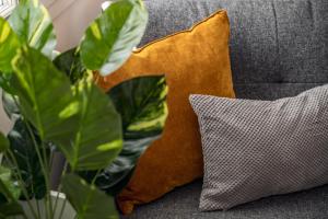 a couch with two pillows and a plant at Pickle Pot Loft- 2 bedroom apartment in Hawkshead in Hawkshead