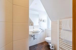 a white bathroom with a sink and a toilet at Hotel am Römerplatz in Ulm