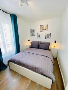 1 dormitorio con 1 cama grande con almohadas moradas en Superbe appartement 2 pièces, plein centre ville. en Montlhéry