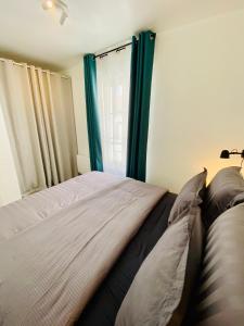 a bedroom with a bed with blue curtains and a window at Superbe appartement 2 pièces, plein centre ville. in Montlhéry