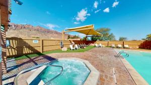 patio trasero con piscina y patio con sombrilla en Arches Abode #A3 en Moab
