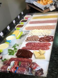 una mesa con diferentes tipos de carne y queso en Aquarius Hotel Flat Residence en Santa Cruz do Sul