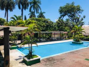a swimming pool in a resort with palm trees at Hotel La Colonia in Retalhuleu