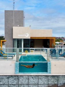 a person laying in a swimming pool on the roof of a building at Hotel Água de Coco in Maceió