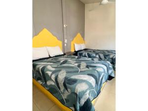 - 2 lits dans une petite chambre avec des draps jaunes et bleus dans l'établissement Hotel Ocean Huatulco, à Santa Cruz Huatulco