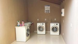 eine Waschküche mit drei Waschmaschinen sowie einer Waschmaschine und einem Trockner in der Unterkunft Apto novo em Condominio com vista as Montanhas. in Serra Negra