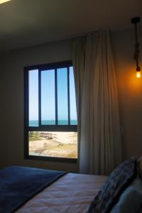 1 dormitorio con ventana y vistas a la playa en Cumbuco - VGSun Apartment 402, en Cumbuco