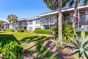 a building with palm trees in front of it at Walk to Beach-Fernandina Shores 6513-Pool & Tennis-On North End Near Main Beach in Fernandina Beach
