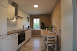 cocina con armarios blancos y mesa de madera en Ferienwohnung in herrlicher Teichlandschaft, 