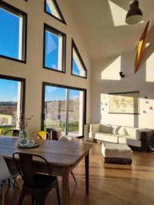 a living room with a table and chairs and windows at Maison contemporaine au cœur de la Roche-Posay in La Roche-Posay