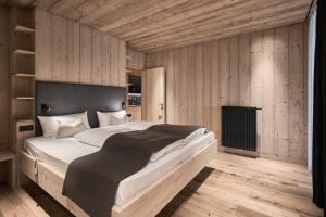 ein Schlafzimmer mit einem großen Bett und Holzwänden in der Unterkunft Tenne Chalets in Ratschings