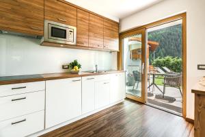 セルヴァ・ディ・ヴァル・ガルデーナにあるAmonit - Your Dolomites Homeの白いキャビネット付きのキッチン、パティオの景色を望む