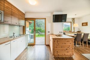a kitchen with wooden cabinets and a dining room with a table at Amonit - Your Dolomites Home in Selva di Val Gardena