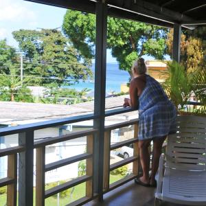 a woman standing on a balcony looking out at the ocean at La Casa de Castara in Castara +6 photos